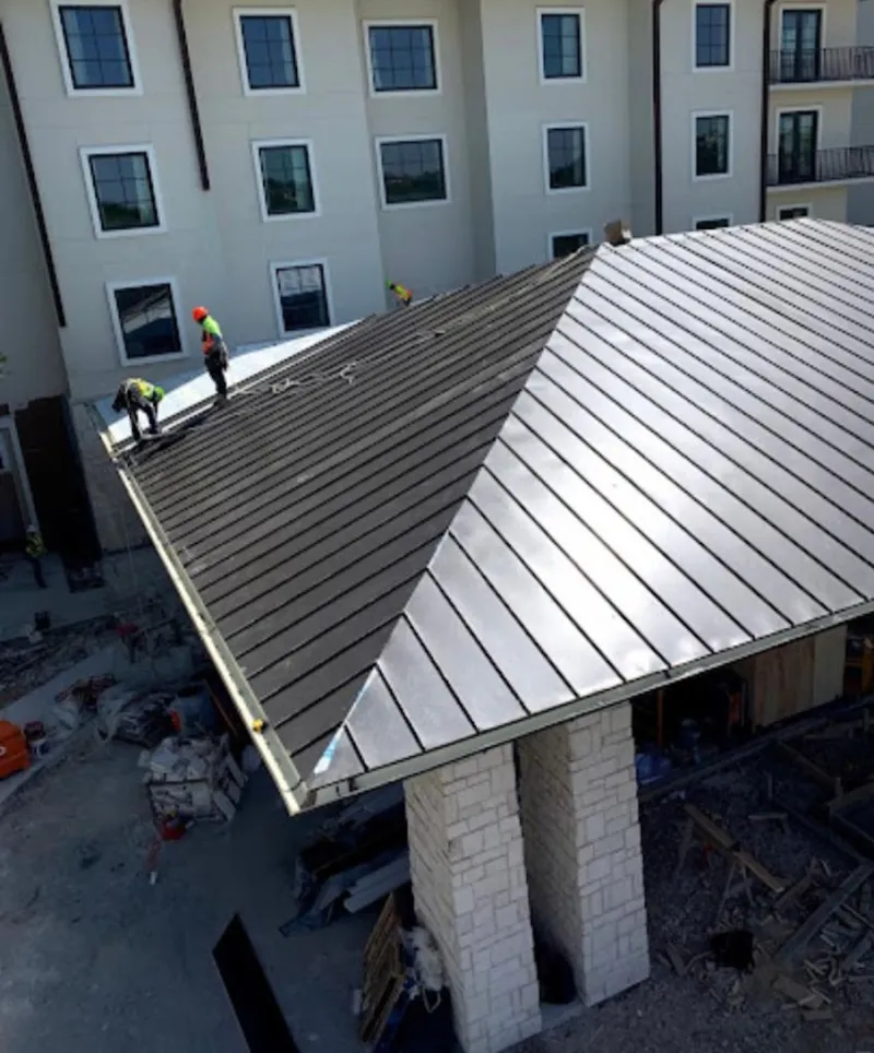 Crew installing standing seam metal roof panels on a commercial project in Layton